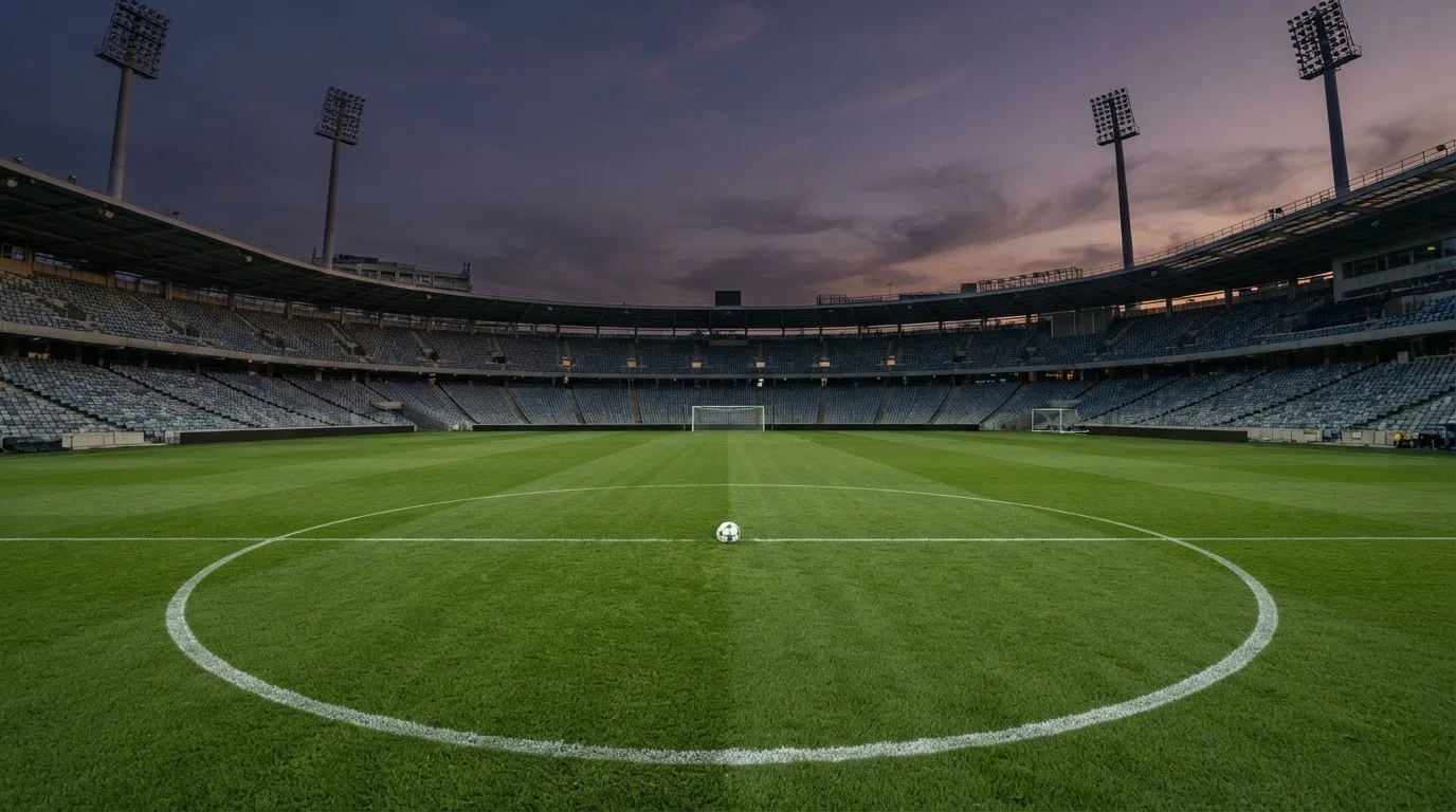 An empty football stadium with floodlight masts at dusk
