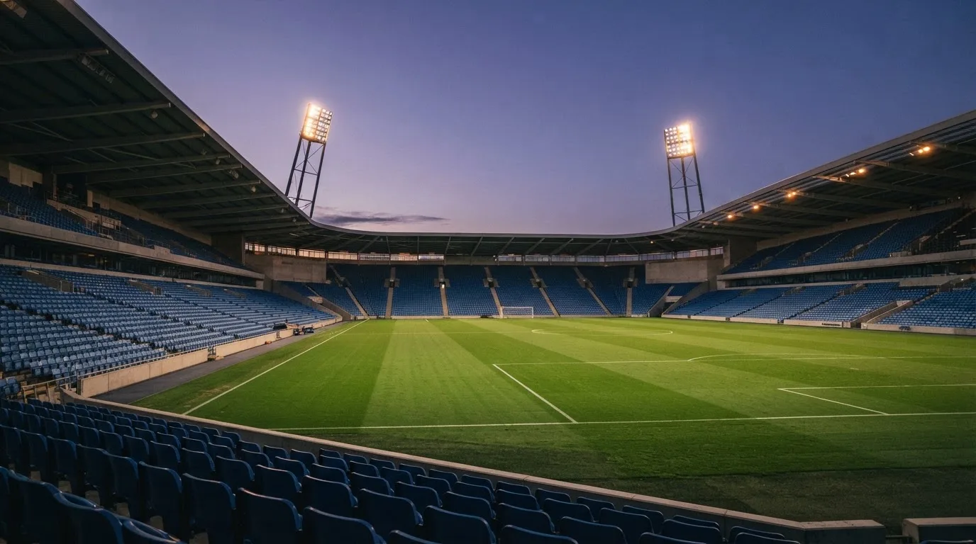 An empty football stadium with floodlight masts at dusk