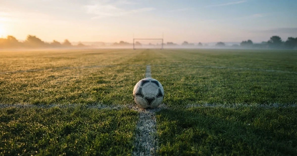 A ball on the centre spot of a grass pitch in morning light