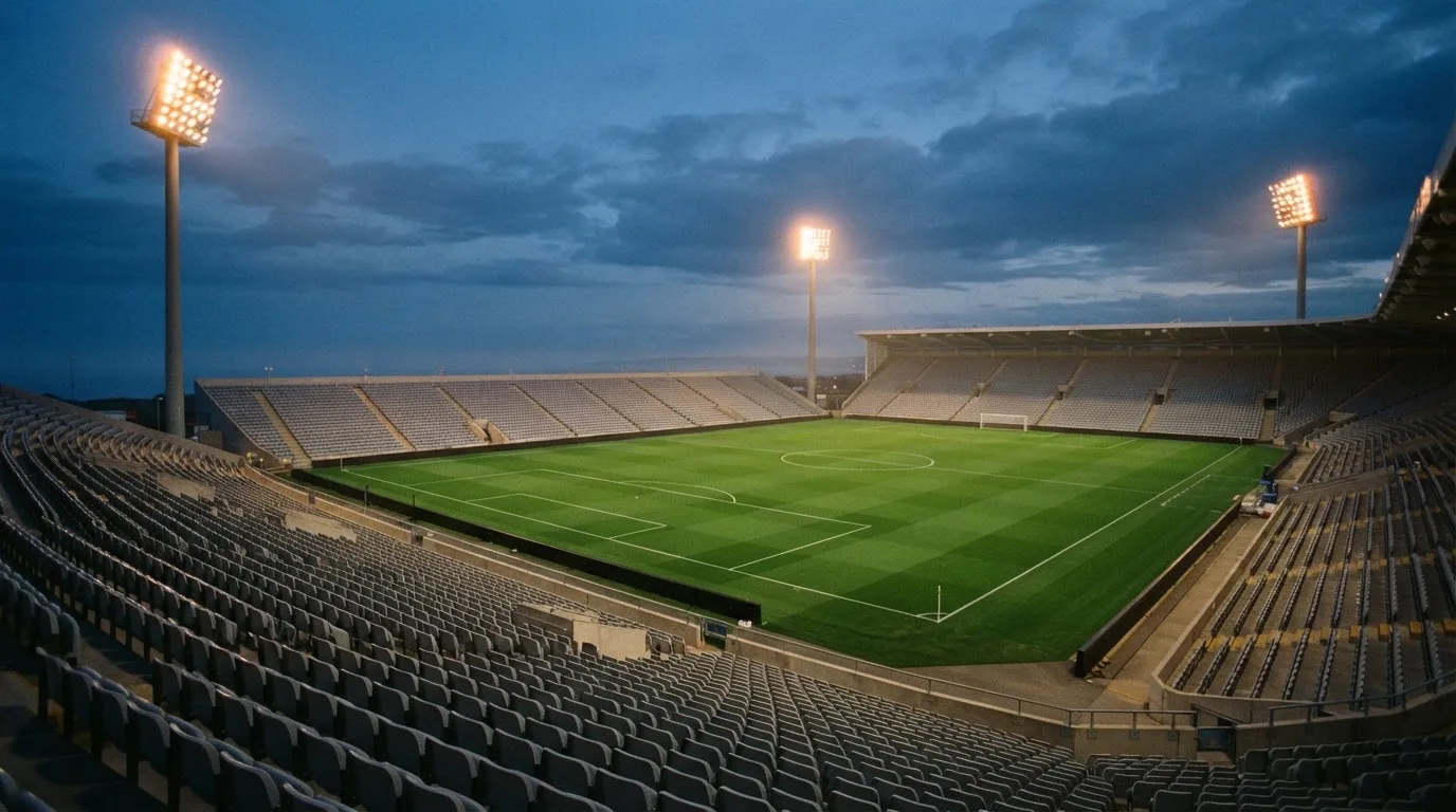 An empty football stadium with floodlight masts at dusk