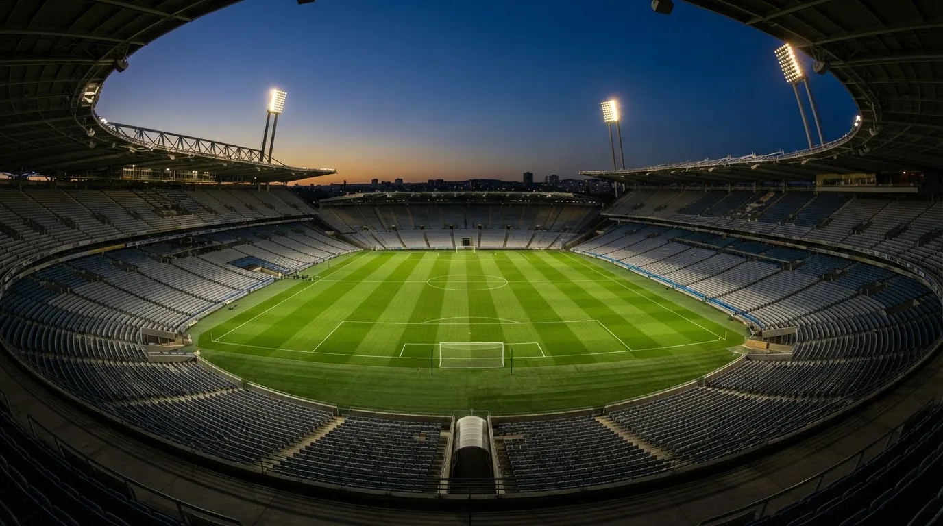 An empty football stadium with floodlight masts at dusk
