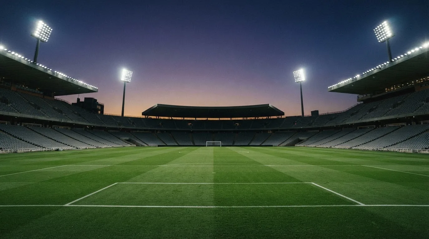 An empty football stadium with floodlight masts at dusk