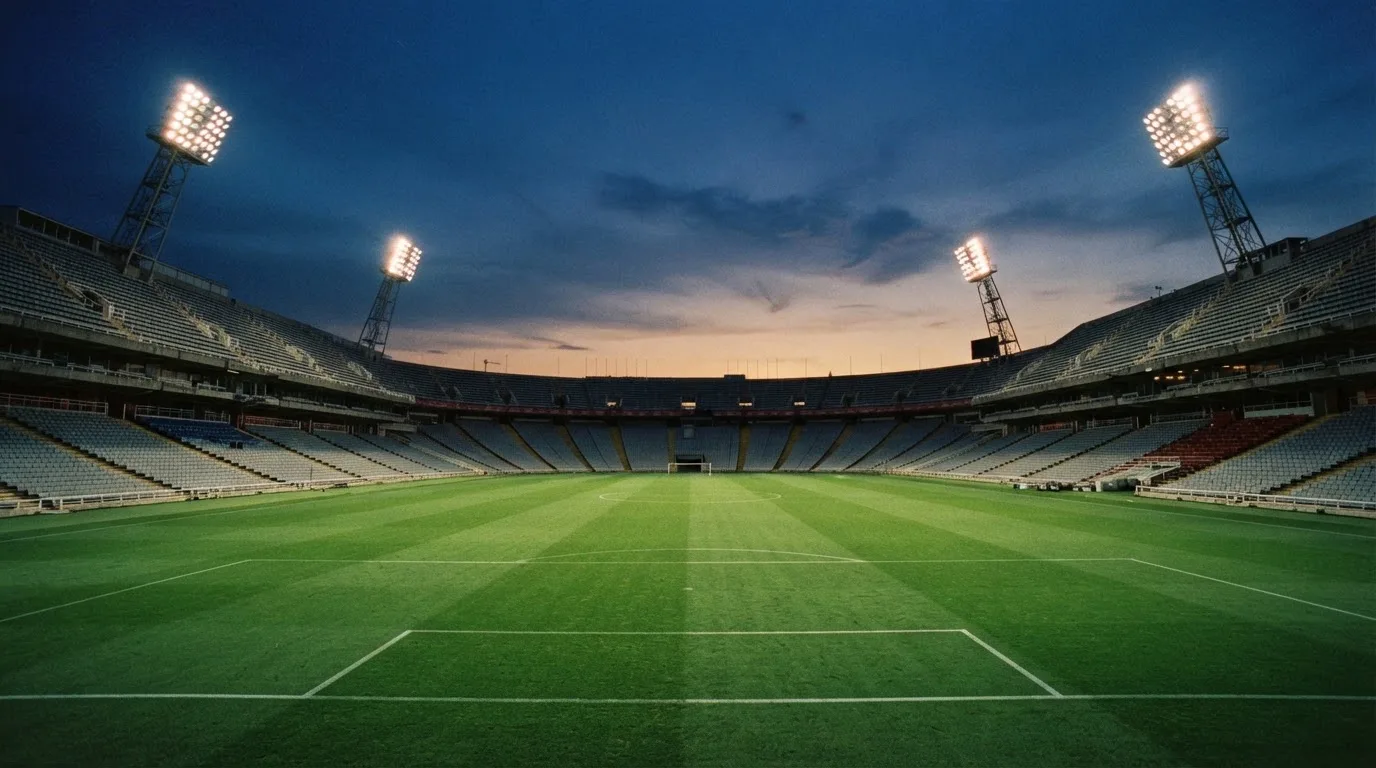 An empty football stadium with floodlight masts at dusk