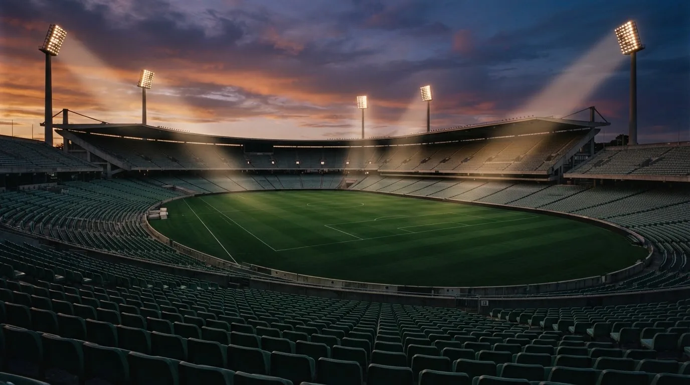 An empty football stadium with floodlight masts at dusk