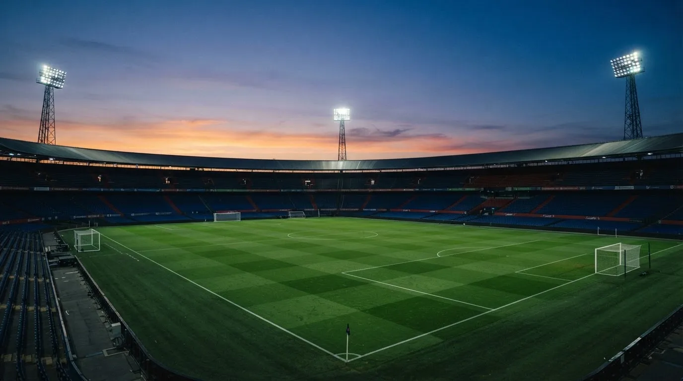 An empty football stadium with floodlight masts at dusk