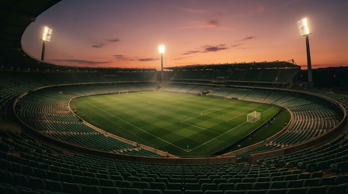 An empty football stadium with floodlight masts at dusk
