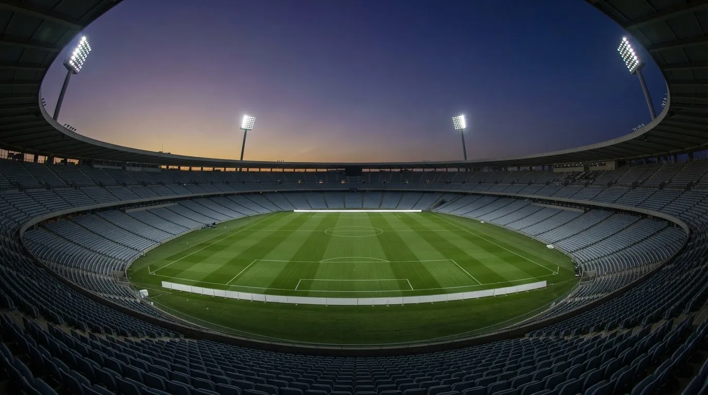 An empty football stadium with floodlight masts at dusk