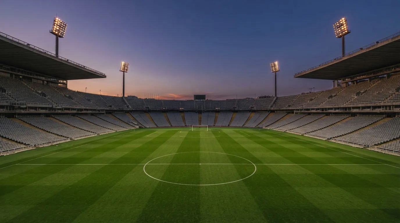 An empty football stadium with floodlight masts at dusk