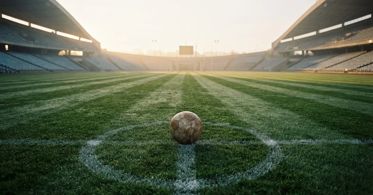 A ball on the centre spot of a grass pitch in morning light