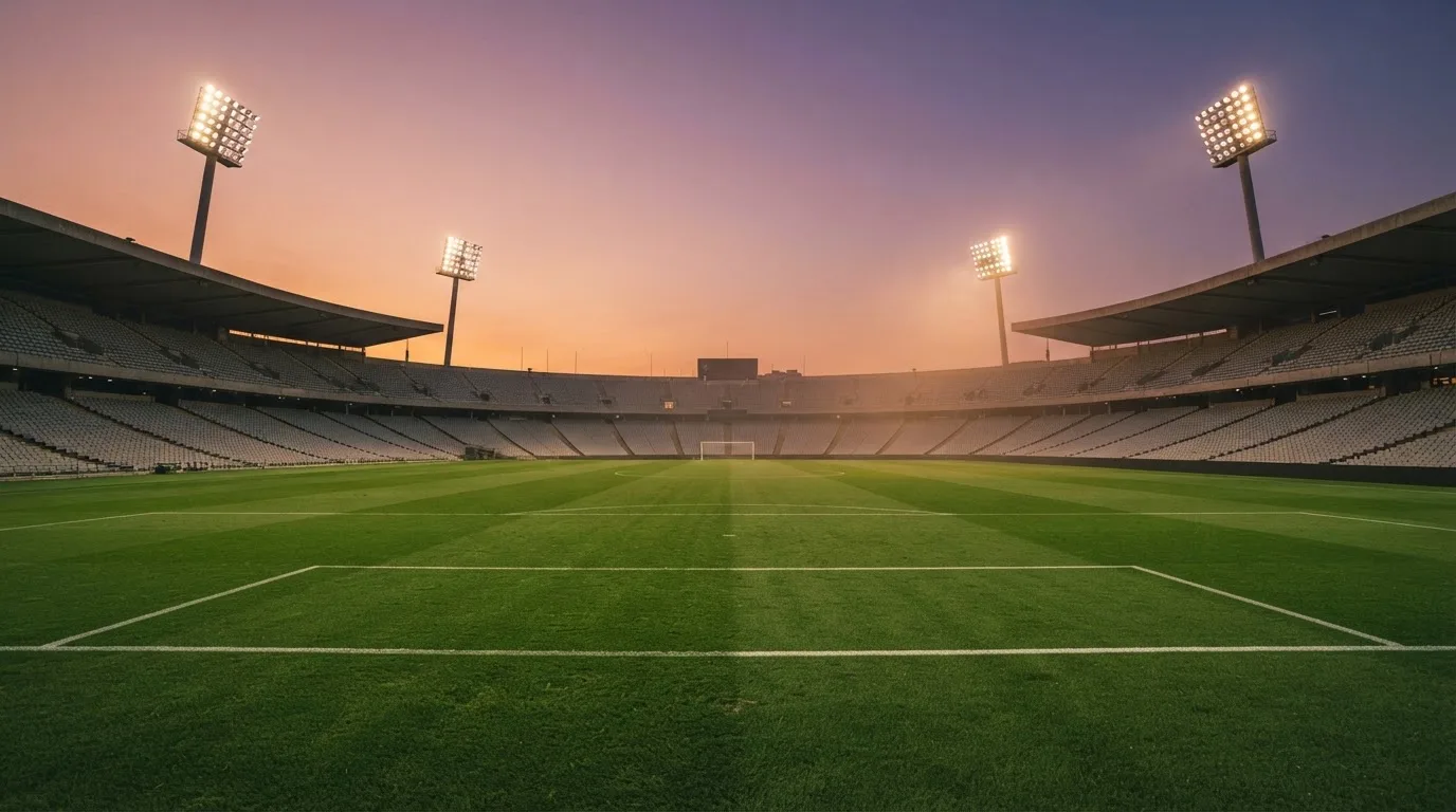 An empty football stadium with floodlight masts at dusk