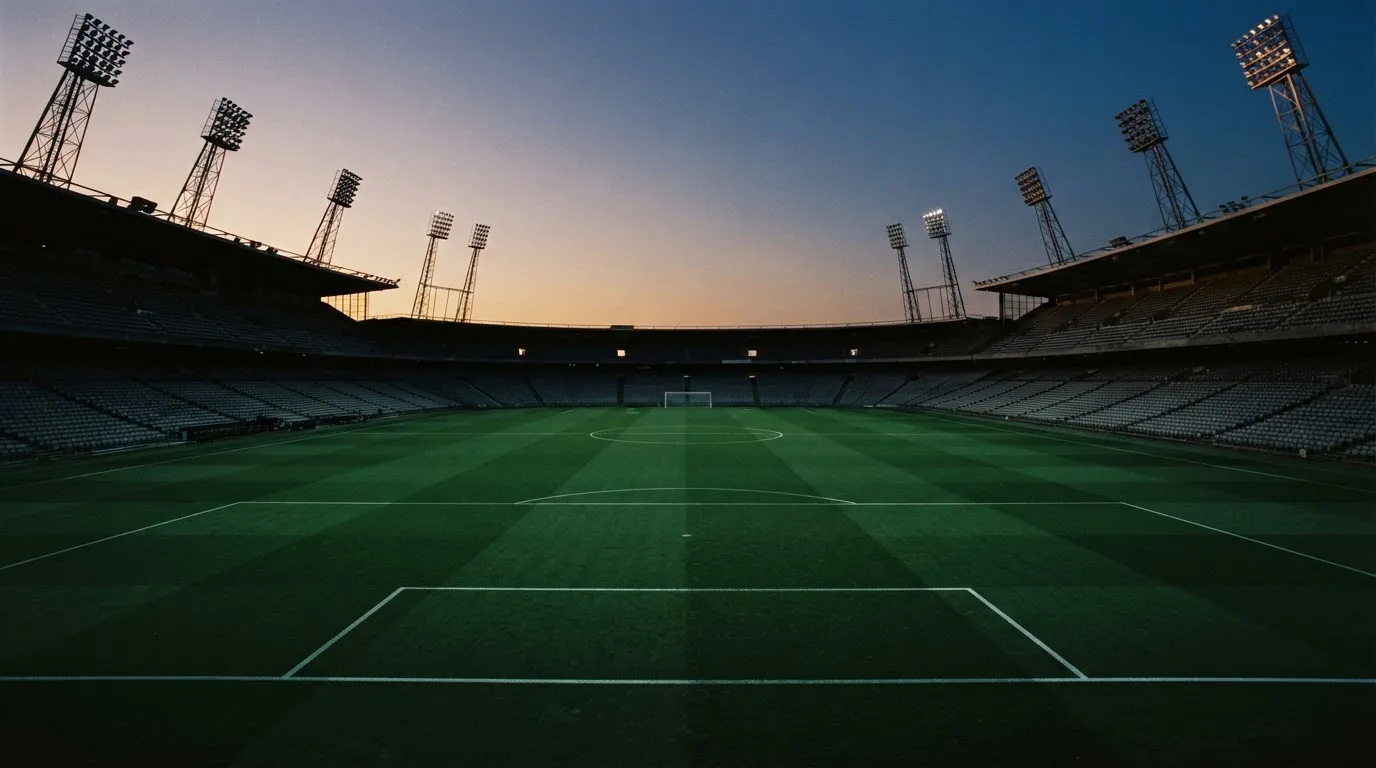An empty football stadium with floodlight masts at dusk