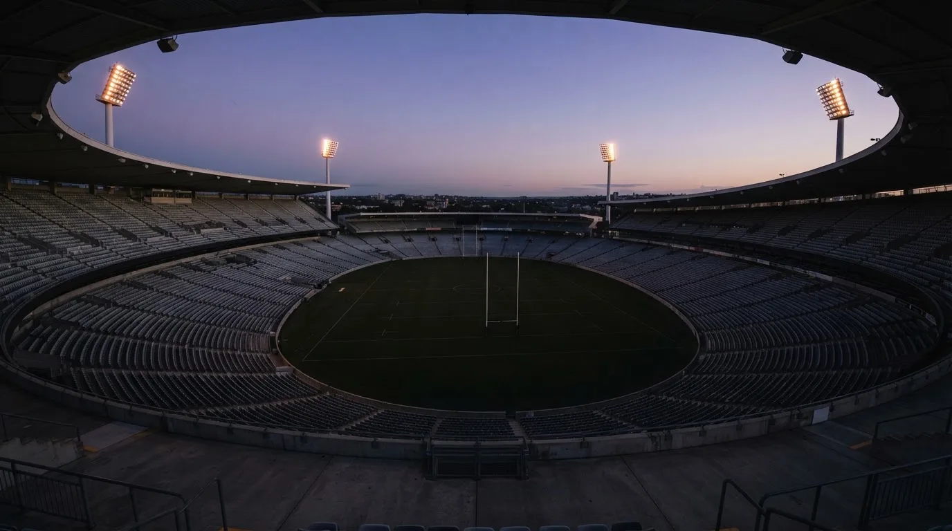 An empty football stadium with floodlight masts at dusk