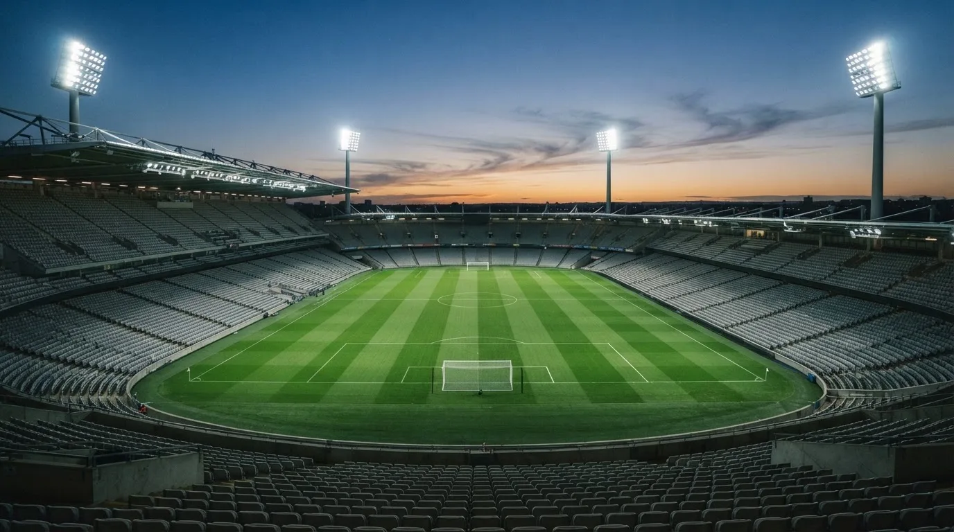An empty football stadium with floodlight masts at dusk