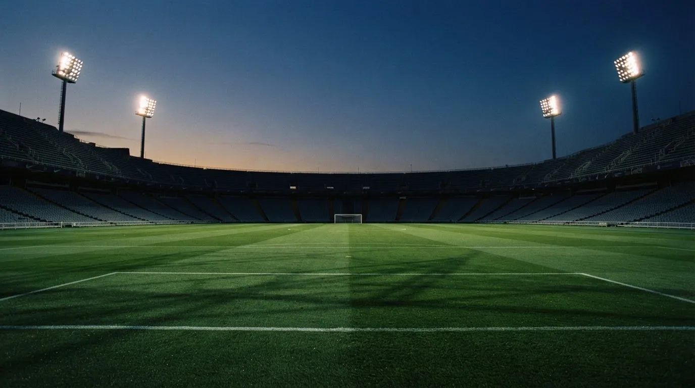An empty football stadium with floodlight masts at dusk