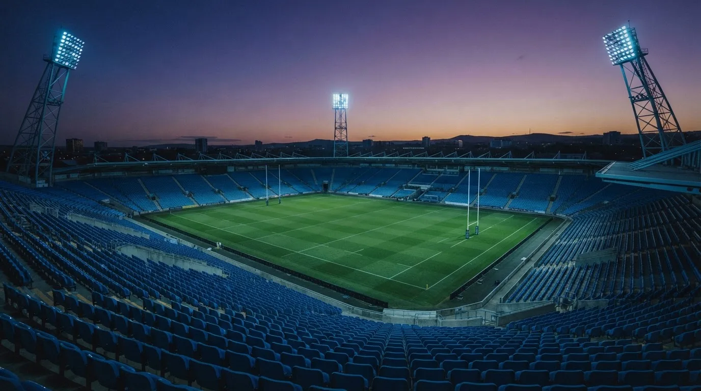 An empty football stadium with floodlight masts at dusk