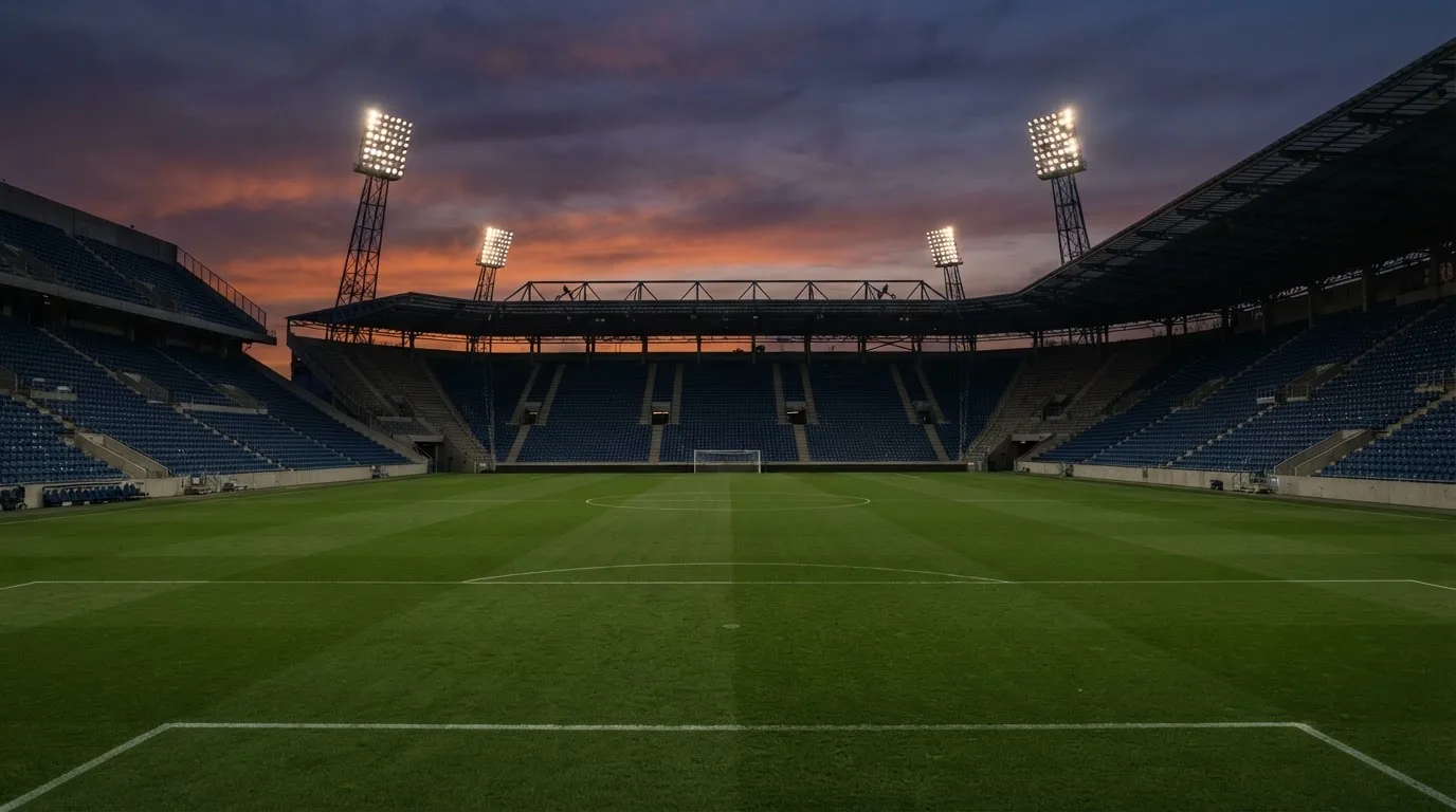 An empty football stadium with floodlight masts at dusk