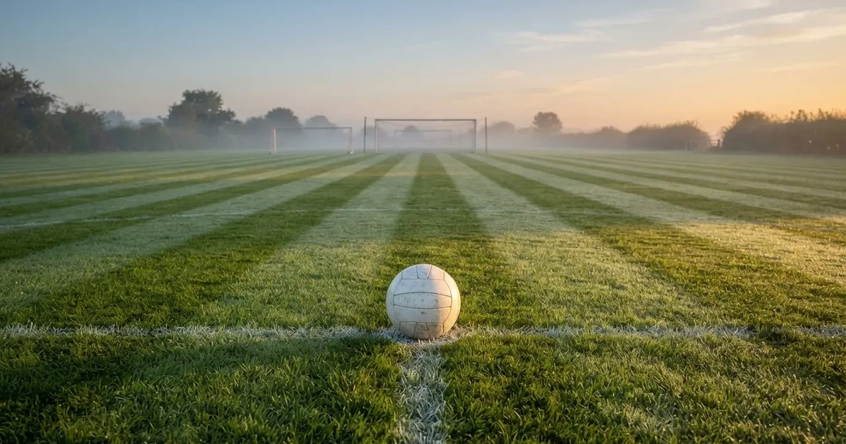 A ball on the centre spot of a grass pitch in morning light
