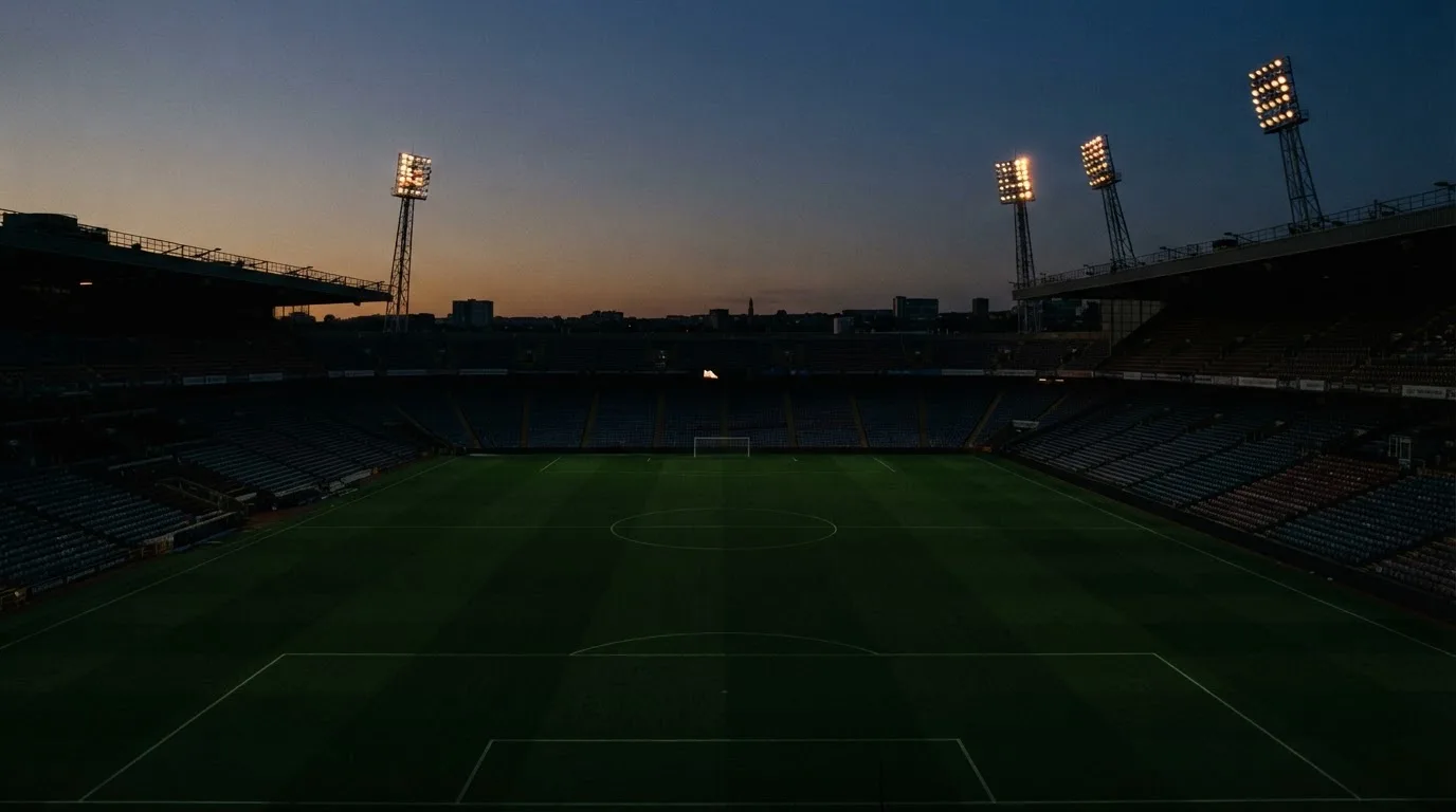 An empty football stadium with floodlight masts at dusk