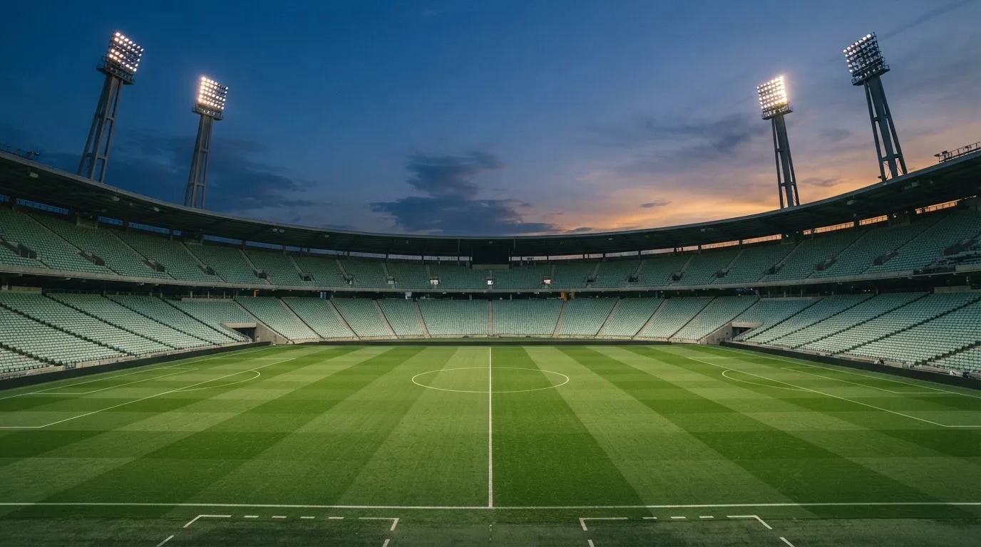 An empty football stadium with floodlight masts at dusk