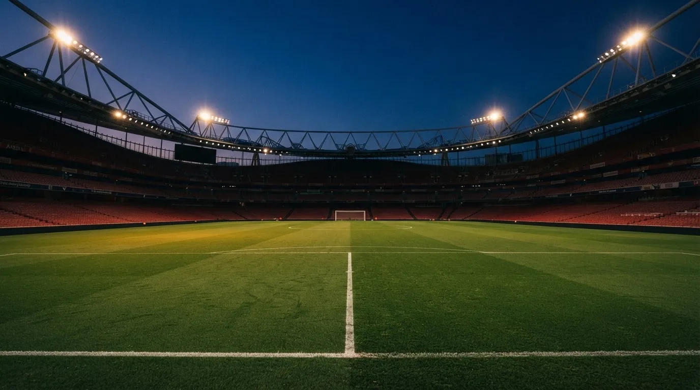 An empty football stadium with floodlight masts at dusk