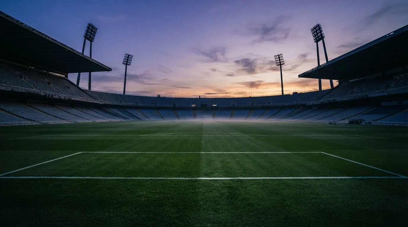 An empty football stadium with floodlight masts at dusk