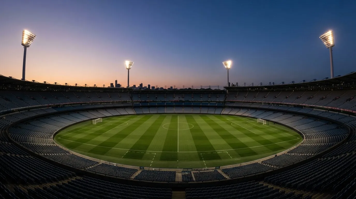 An empty football stadium with floodlight masts at dusk