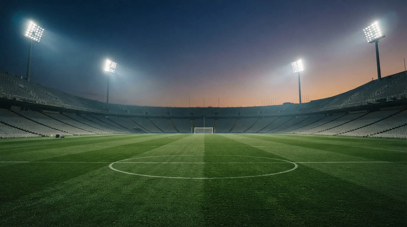 An empty football stadium with floodlight masts at dusk