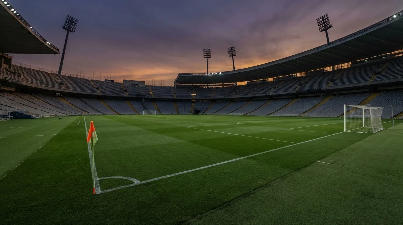 An empty football stadium with floodlight masts at dusk