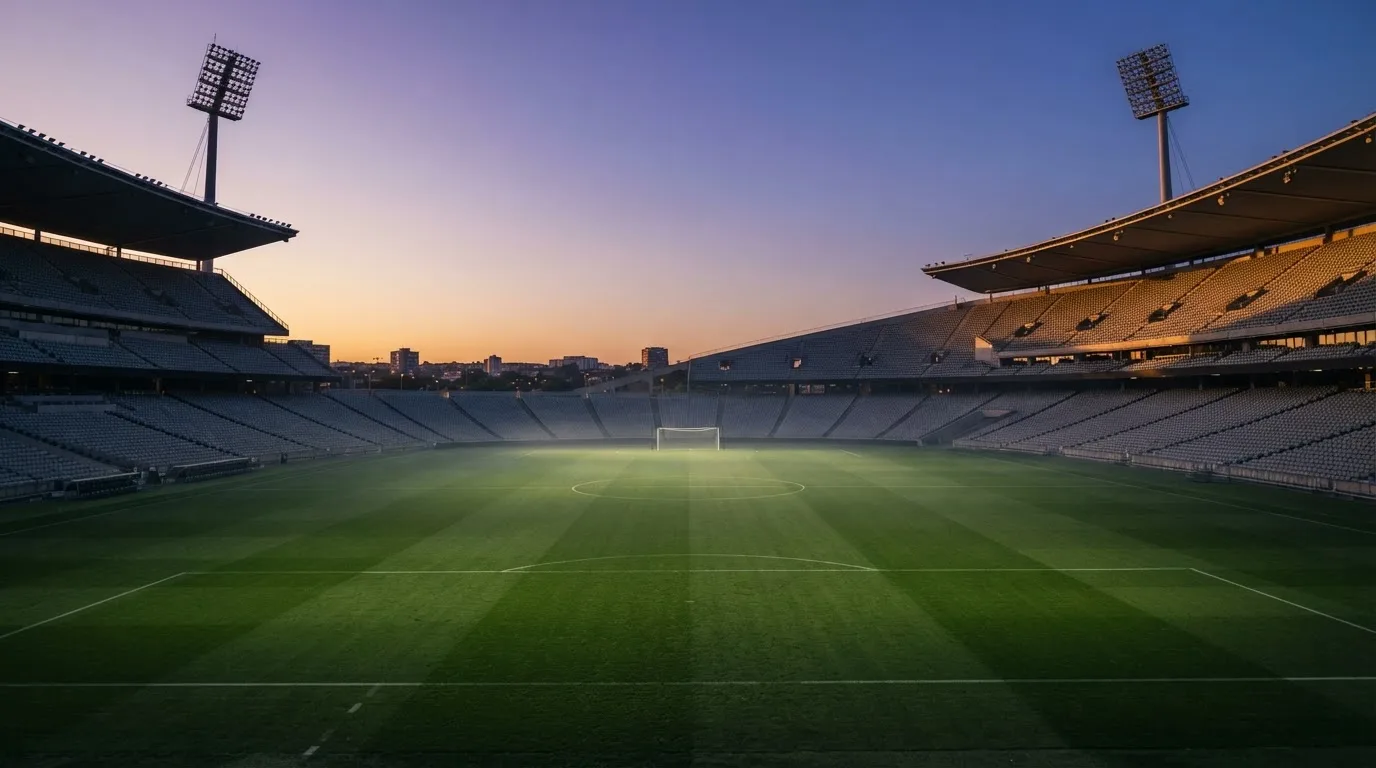 An empty football stadium with floodlight masts at dusk