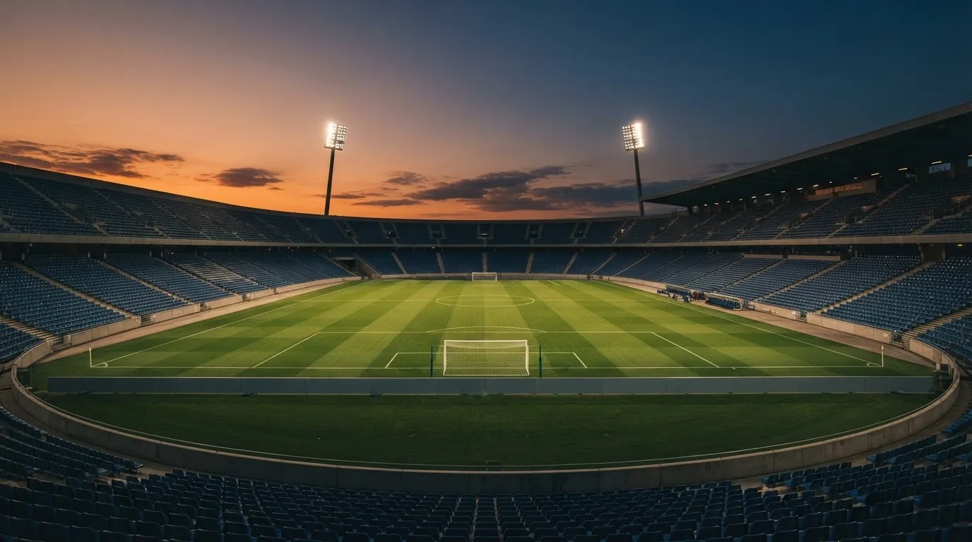 An empty football stadium with floodlight masts at dusk