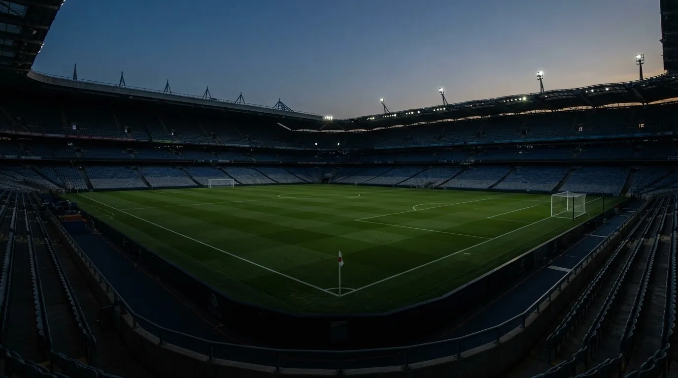 An empty football stadium with floodlight masts at dusk