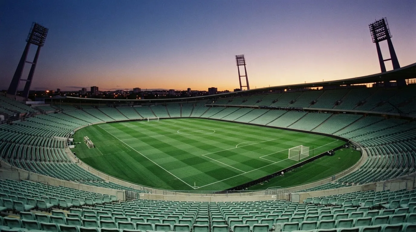 An empty football stadium with floodlight masts at dusk