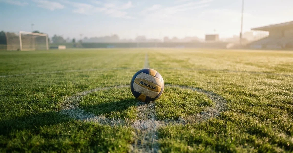 A ball on the centre spot of a grass pitch in morning light